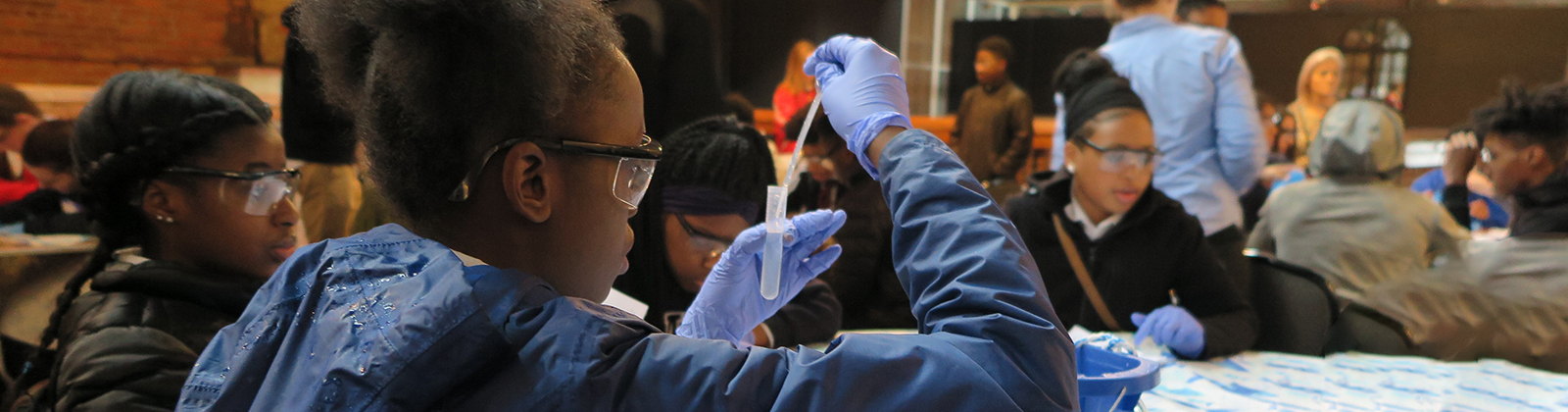 Student testing water with a test tube and dropper.