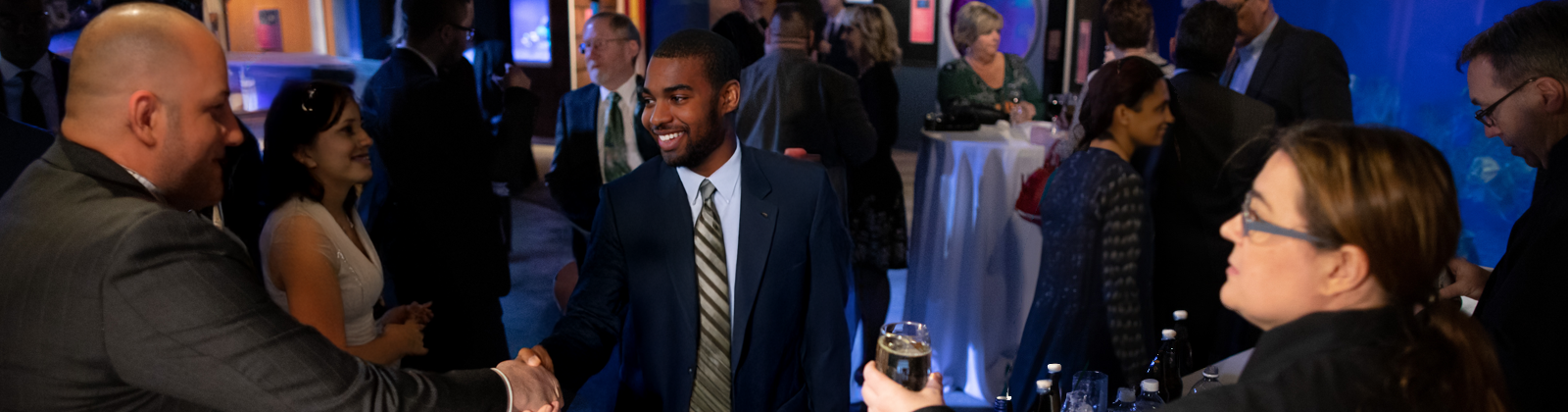 People shaking hands in the Coastal Gallery at a cocktail reception